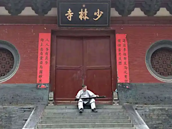 Mark playing a Guqin on the front steps of the Shaolin Temple in China.